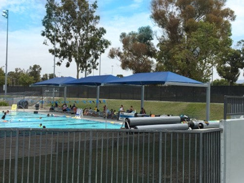 A swimming pool with a Heavy Duty Cantilever Shade Structure by Shade Structures.